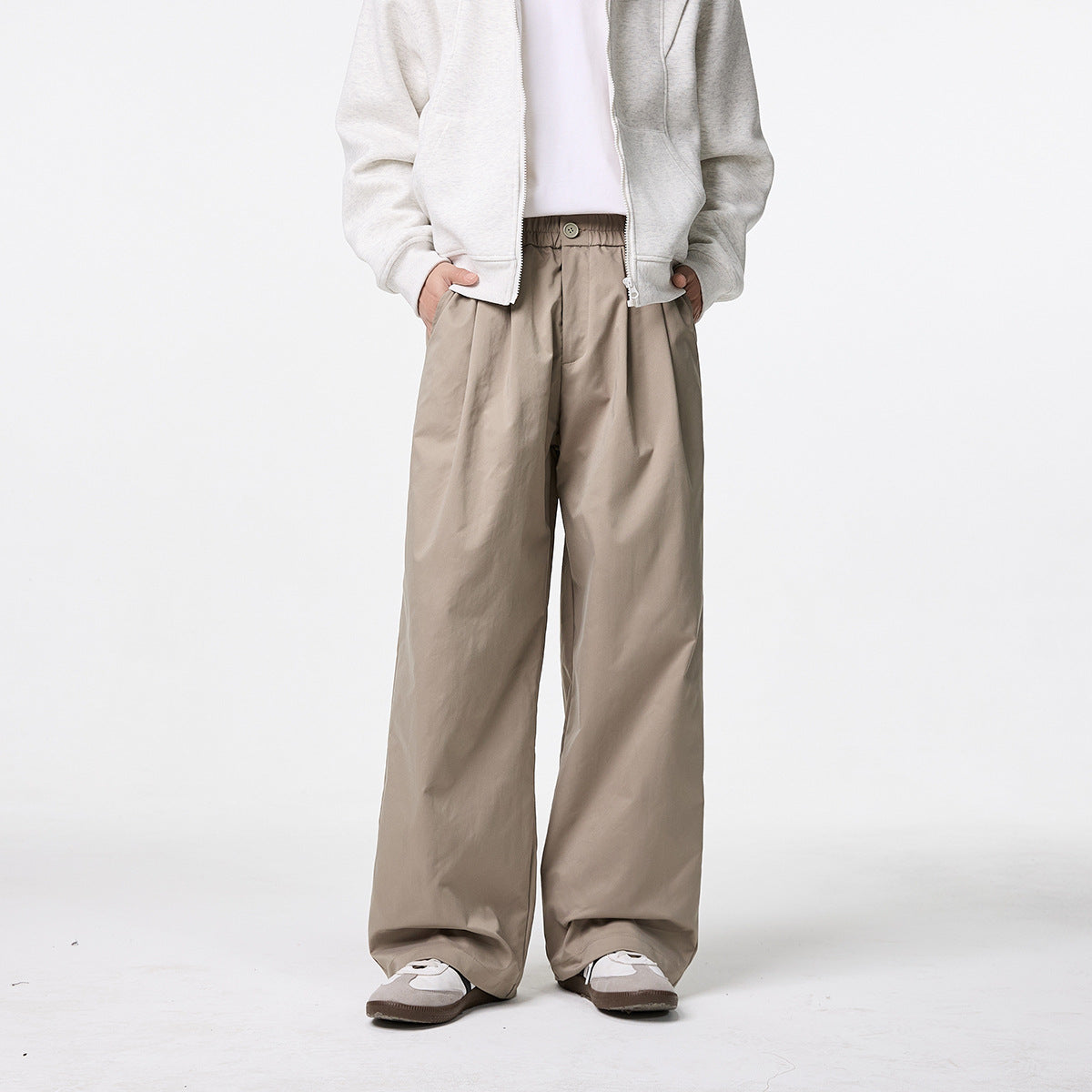 Front view of a model wearing taupe wide-leg trousers with a button waist and a light zip hoodie.