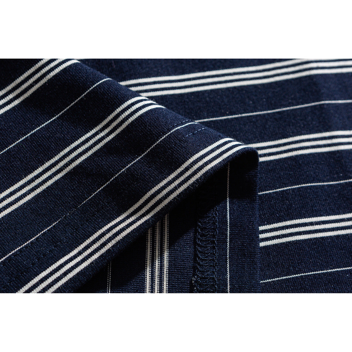 Close-up of navy fabric with thin white stripes and a folded, stitched edge.