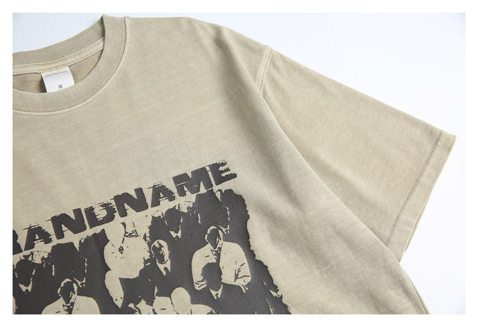 Close-up of a sand-beige T-shirt shoulder and sleeve with part of a dark graphic print.