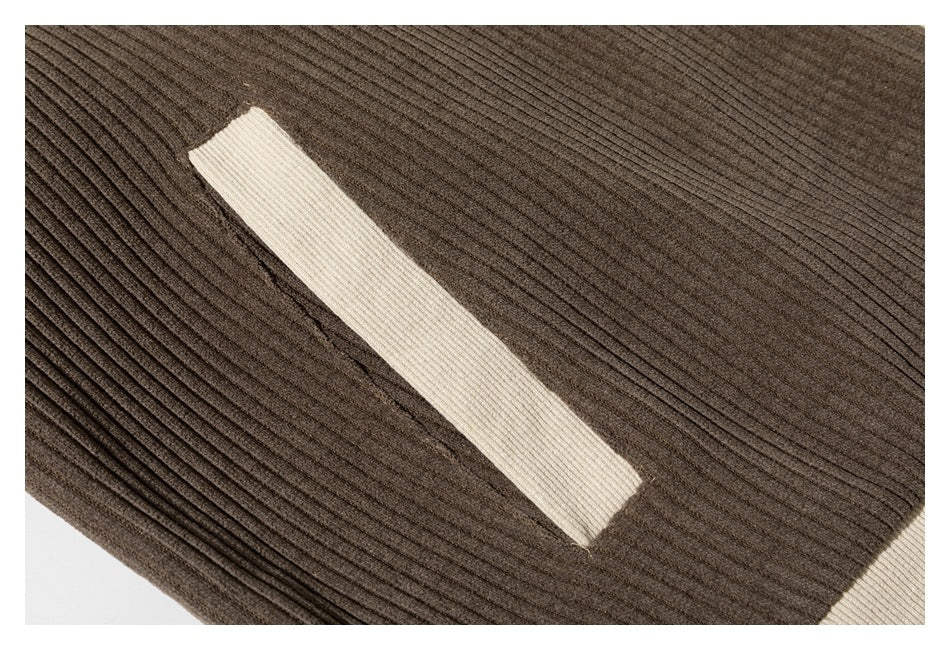 Close-up of a cream welt pocket on brown ribbed fabric.