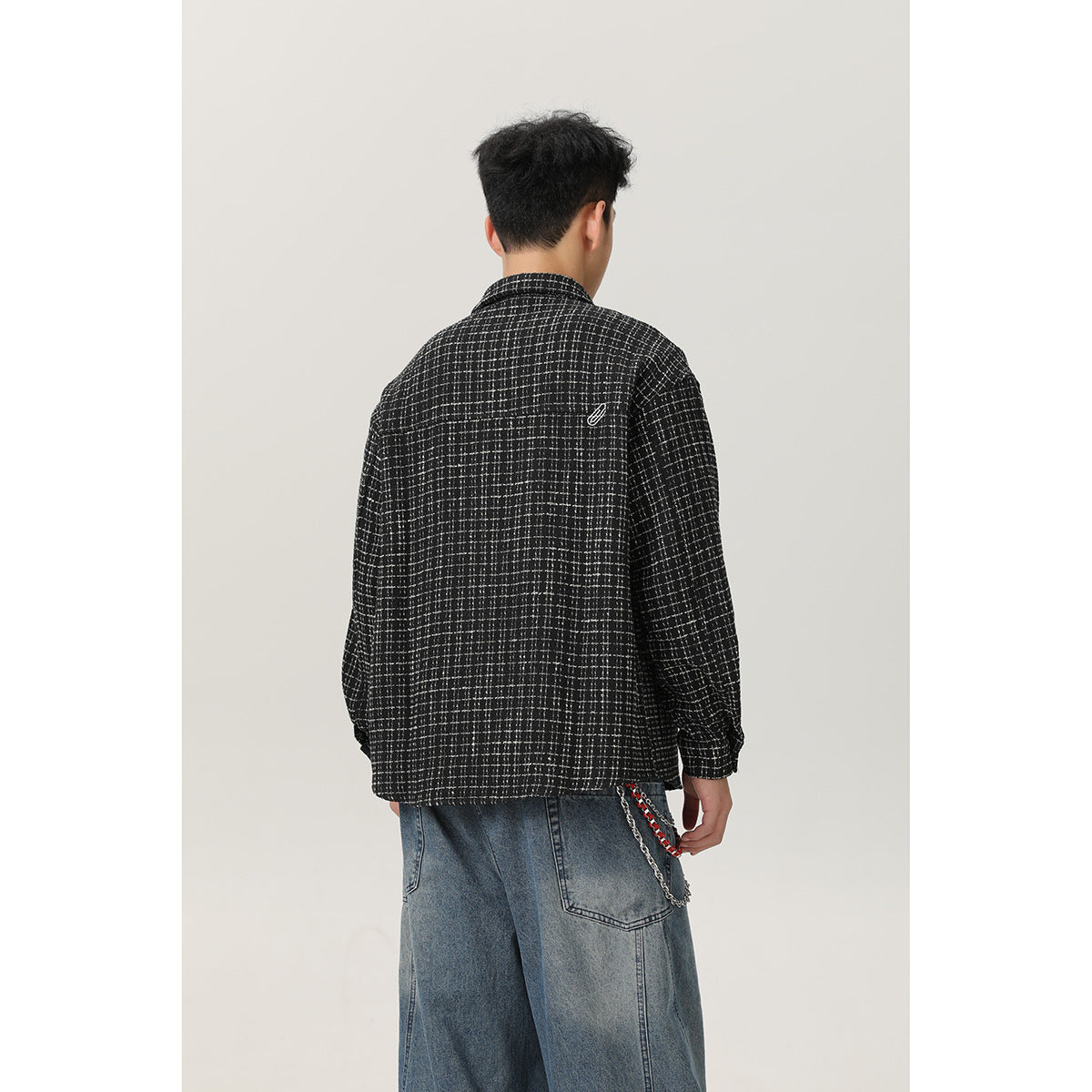 Back view of a model wearing a black-and-white grid overshirt with long sleeves.