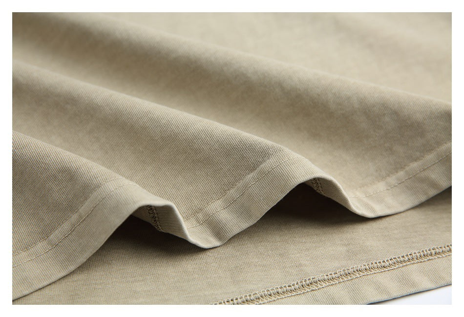 Close-up of beige garment fabric showing a curved hem and overlocked stitching.
