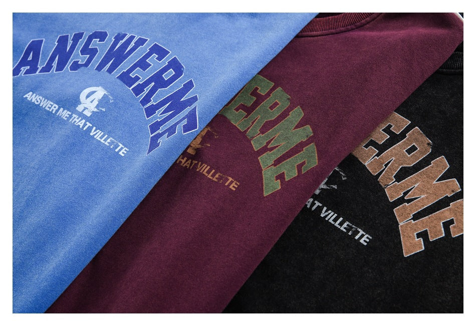 Close-up of blue, burgundy, and black sweatshirts with large printed English lettering in contrasting colors.