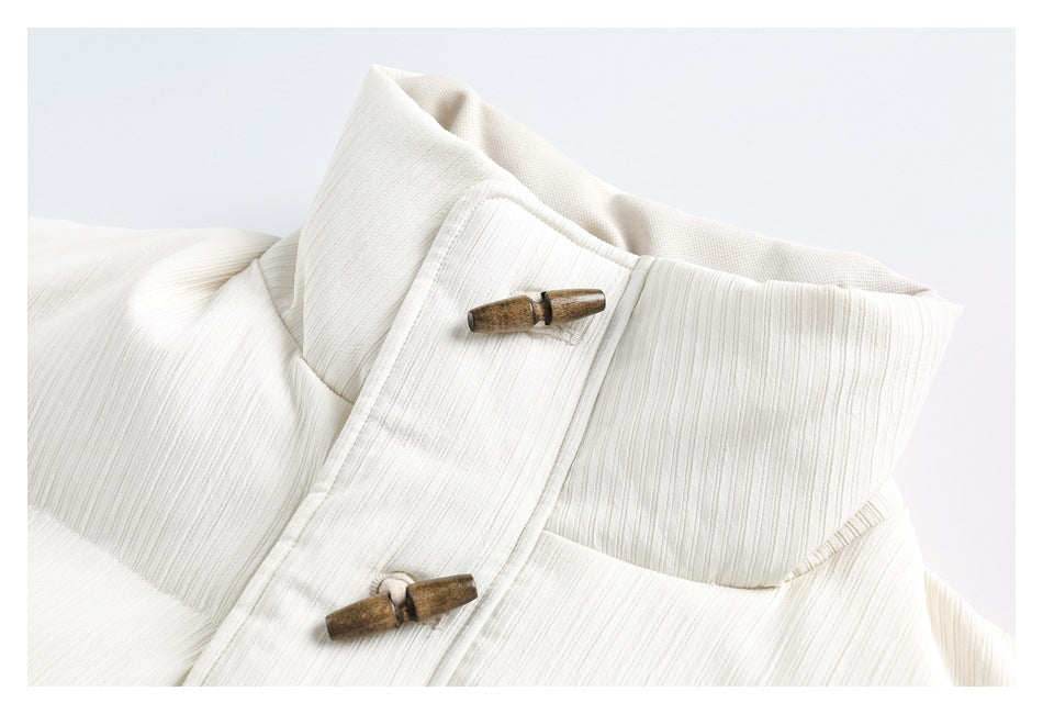 Close-up of an ivory jacket's high collar and front placket with two wooden toggle fasteners.