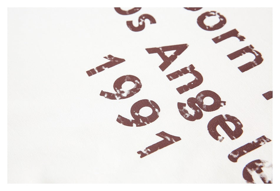 Close-up of distressed dark brown lettering printed on white fabric.