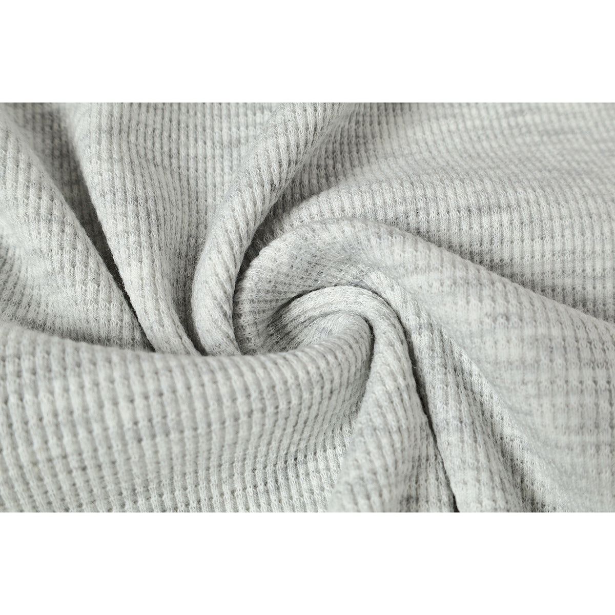 Close-up of light gray ribbed fabric gathered into a spiral to show its texture.