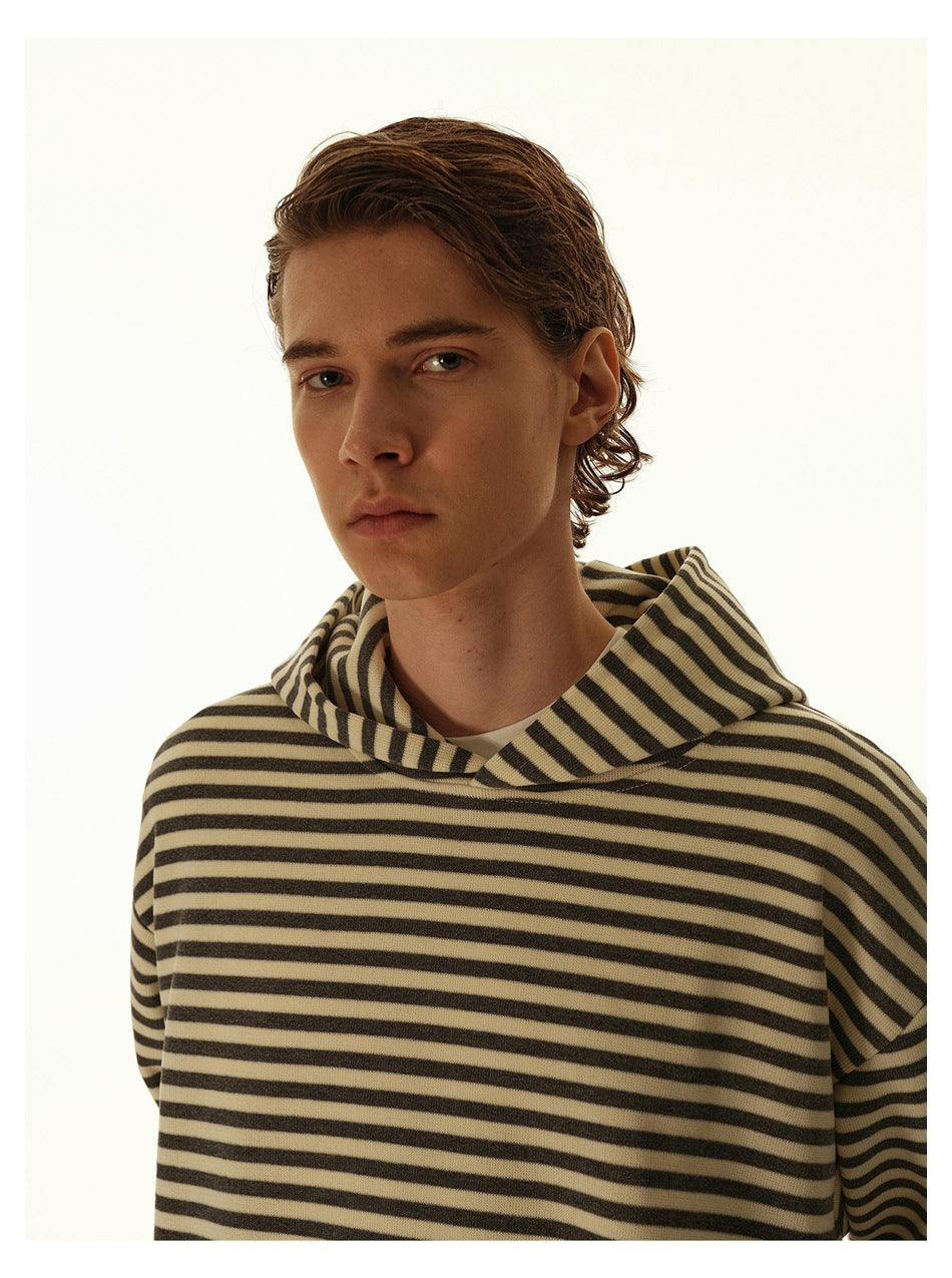 Close-up of a model wearing a beige and dark striped hooded sweatshirt, showing the hood and upper front.