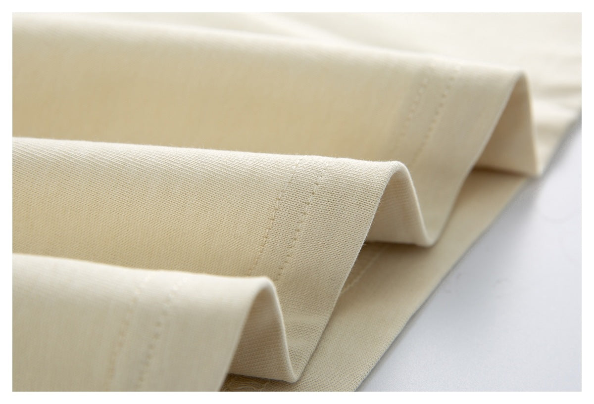 Close-up of the ivory shirt's folded bottom hem with parallel rows of stitching.