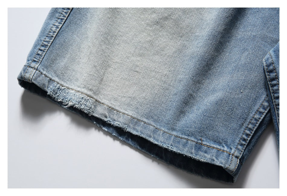 Close-up of a light blue denim shorts leg with a raw, frayed hem.