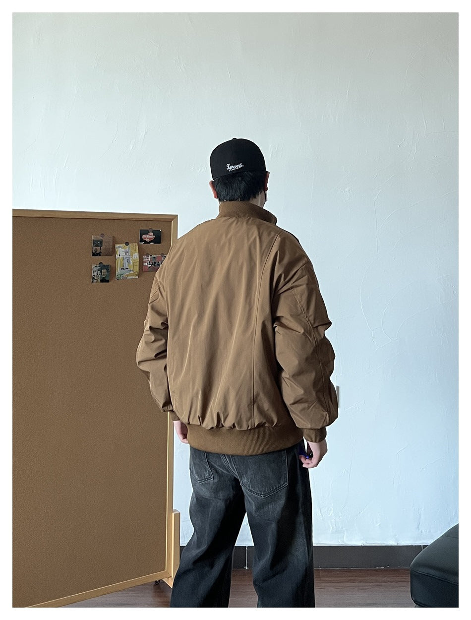 Back view of a person wearing the brown puffer jacket with ribbed stand collar and hem, with dark jeans and black cap