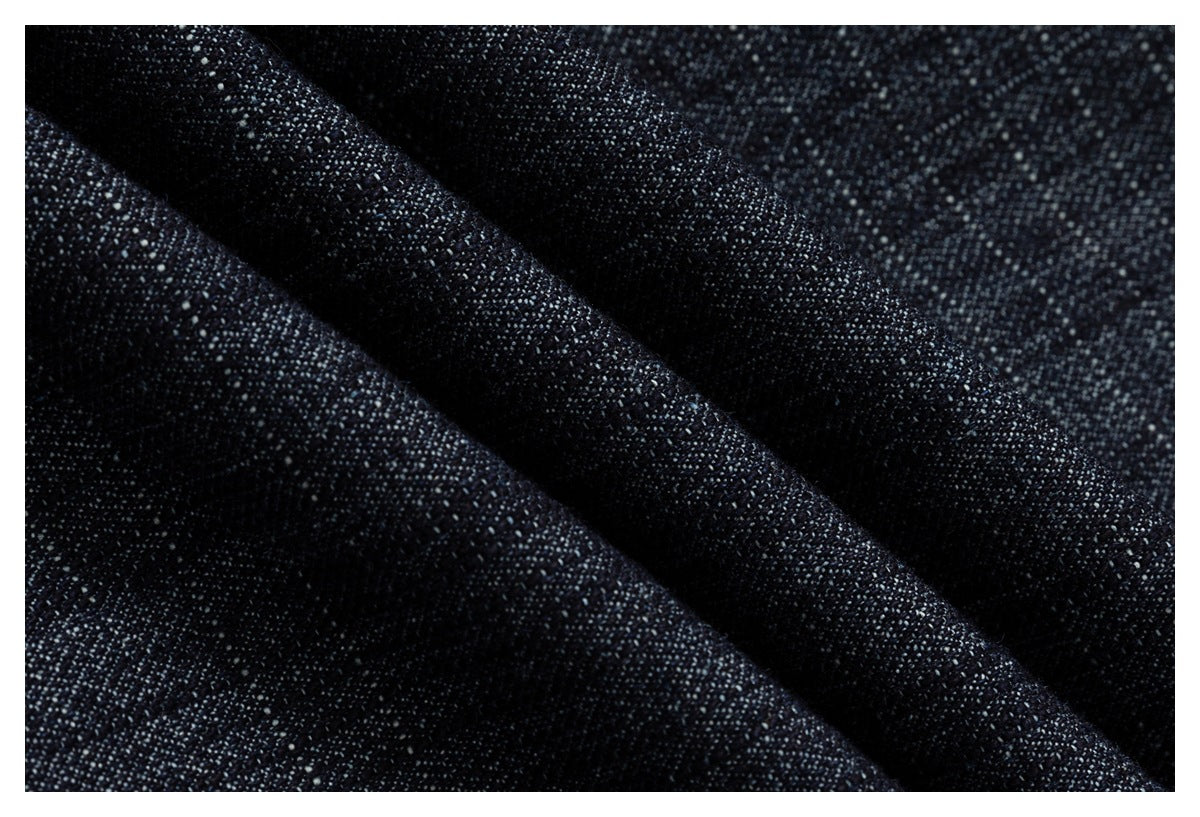 Close-up of dark indigo denim fabric folded to show its textured weave.