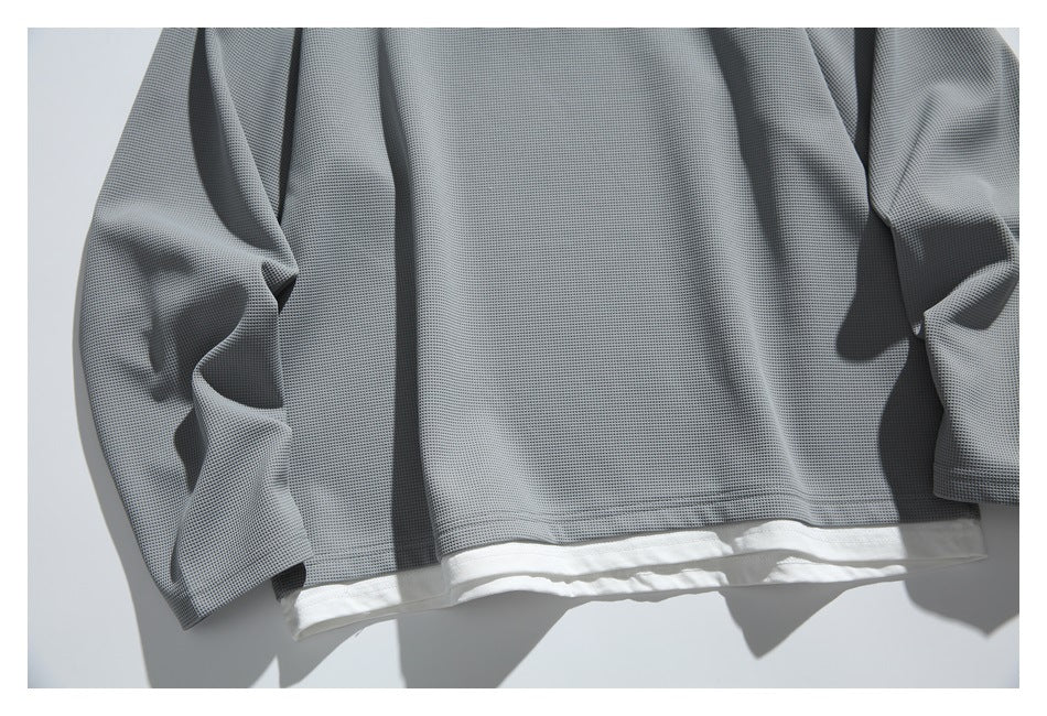 Close-up of the gray top's textured fabric, sleeves, and layered white hem.