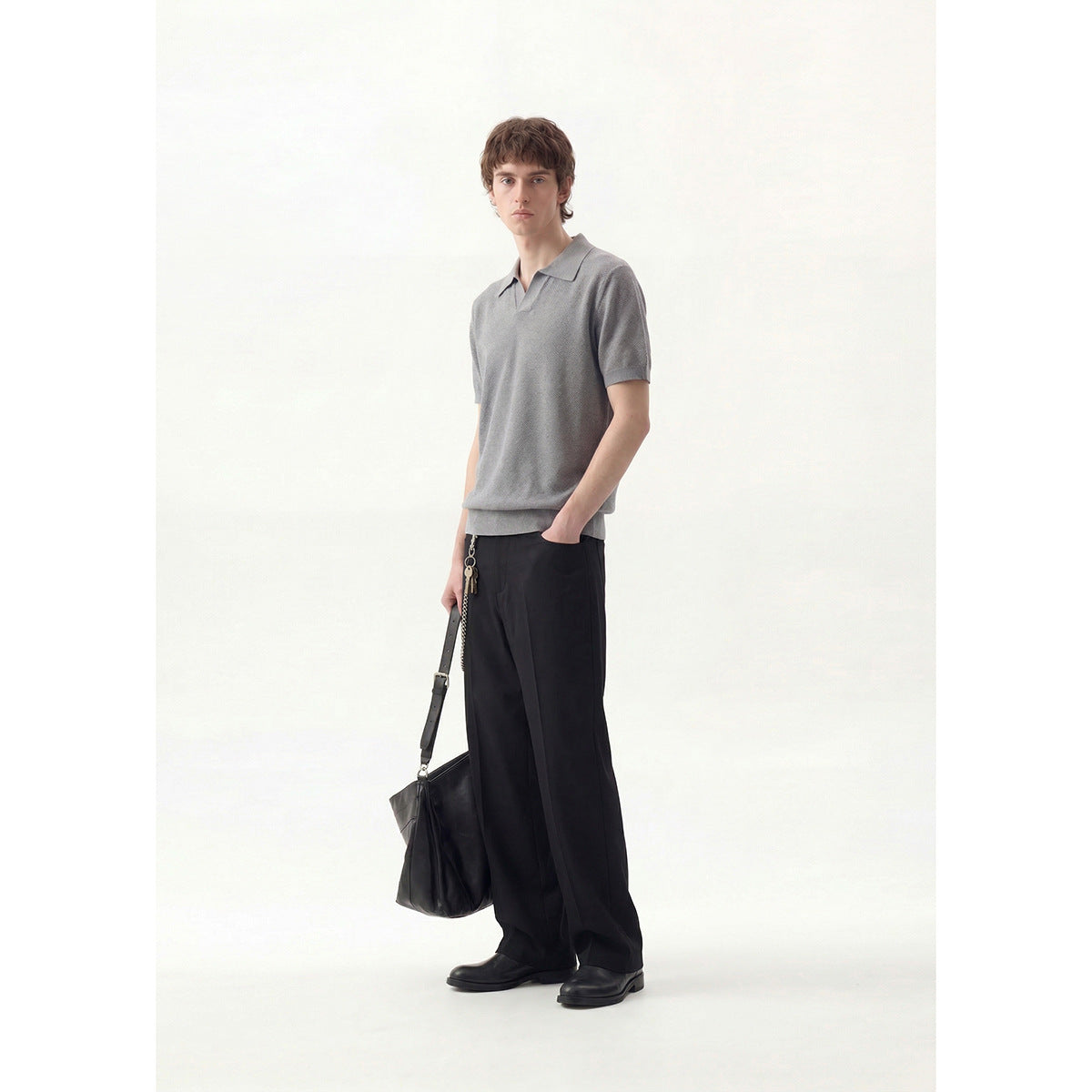 Model wearing a gray short-sleeve polo with black wide-leg trousers, shown full length from the front.