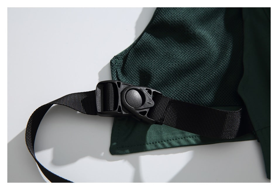 Close-up of a black buckle and strap across dark green mesh and solid fabric.