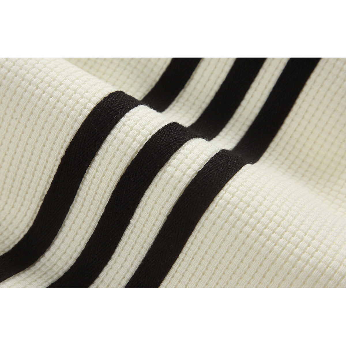 Close-up of three black stripes on ivory textured jacket fabric.