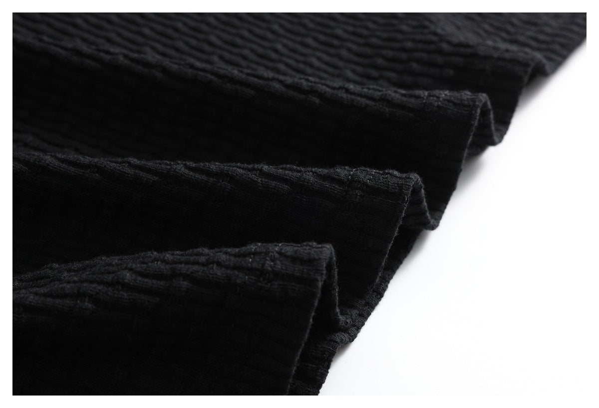 Close-up of several folded edges of the black ribbed garment.