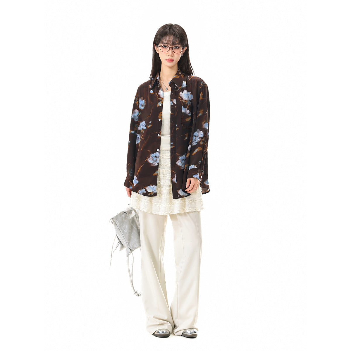Full-length model wearing an oversized dark brown button-up shirt with blue floral print over cream layers.