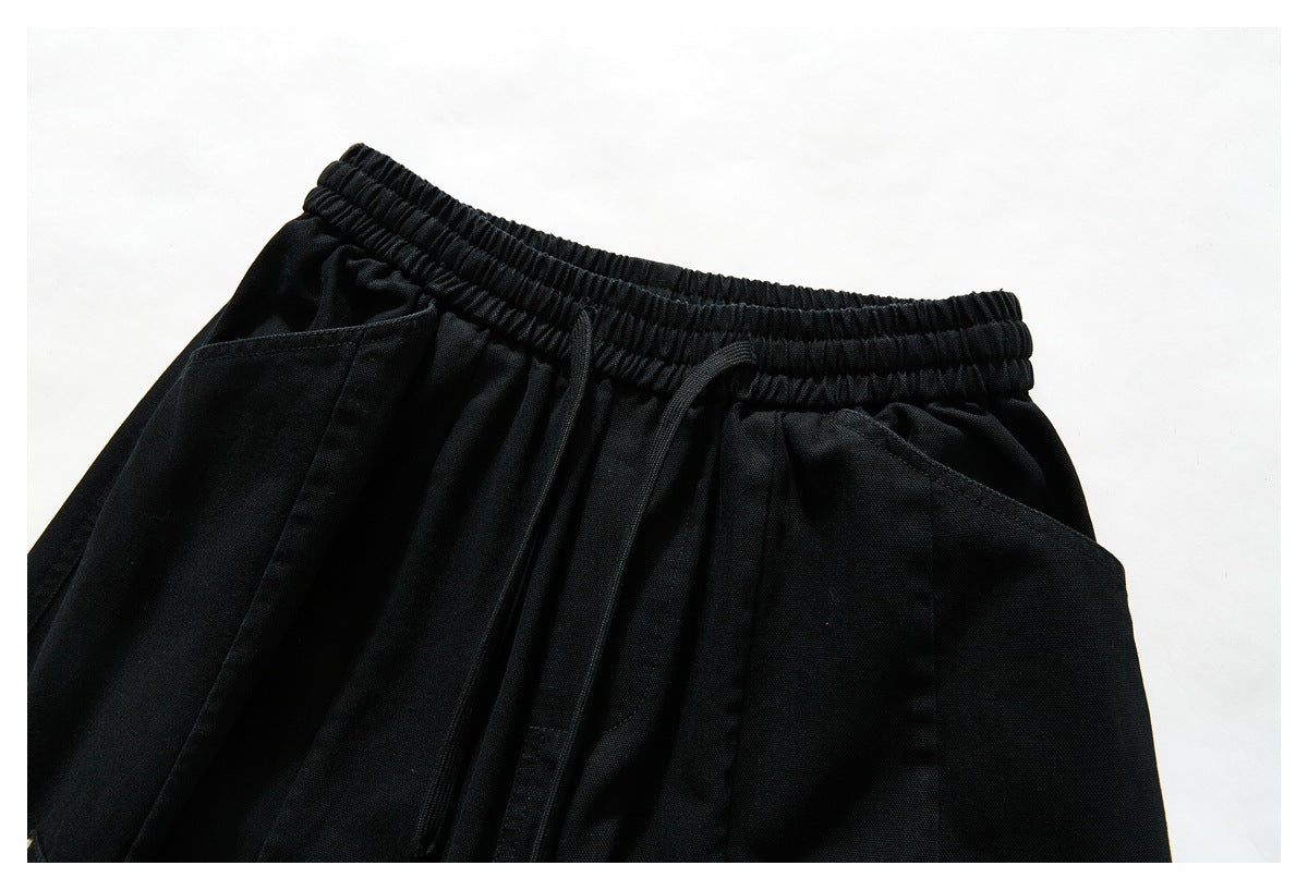 Close-up of black pants showing the elastic drawstring waistband and front pocket openings.
