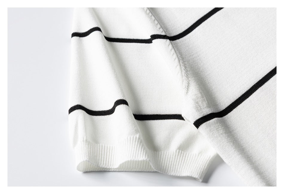 Close-up of a white knit sweater sleeve and ribbed cuff with thin black horizontal stripes.