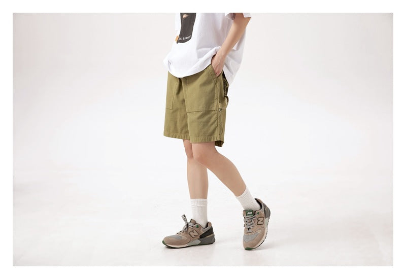 Angled side view of a model wearing olive-green shorts with roomy patch pockets.