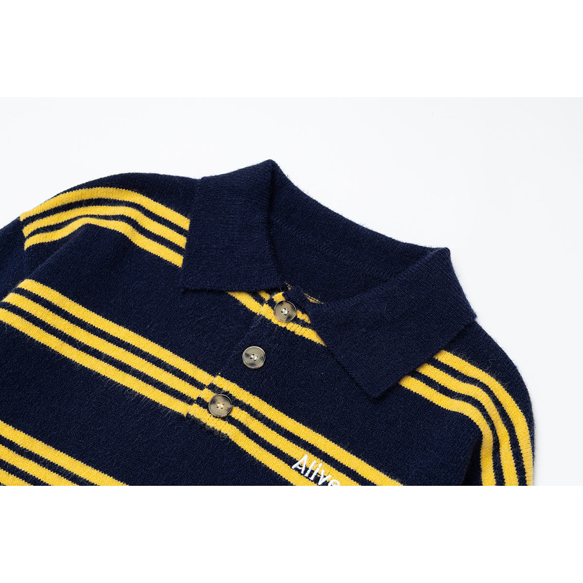 Close-up of a navy knit polo sweater with yellow stripes, a pointed collar, buttons and small white chest embroidery.
