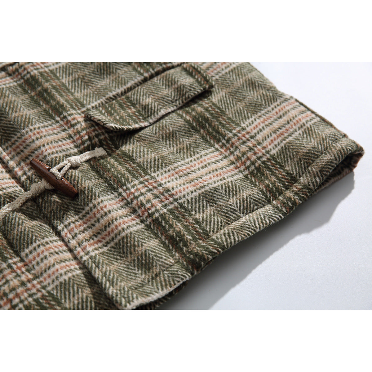 Close-up of a plaid jacket pocket flap, toggle closure, and stitched hem.