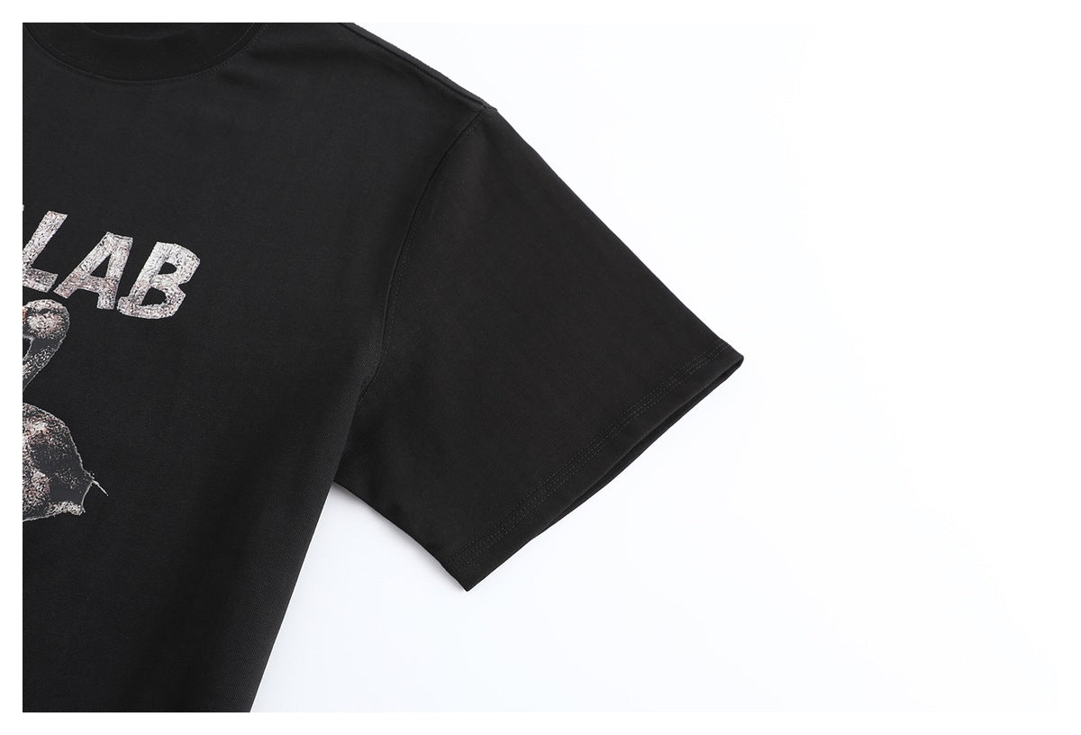 Cropped view of a black T-shirt front and short sleeve, showing part of its silver graphic print.