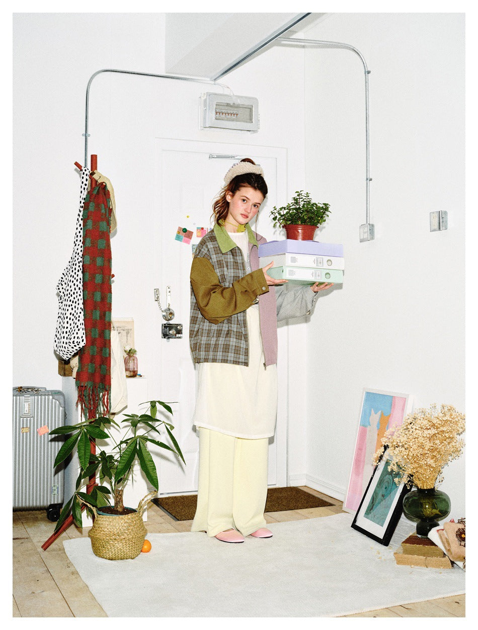 Model wearing a multicolor color-block jacket with a gray-brown plaid front, green collar, and contrasting sleeves.