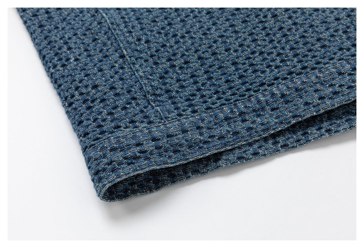 Close-up of the folded edge and seam of blue textured woven fabric.