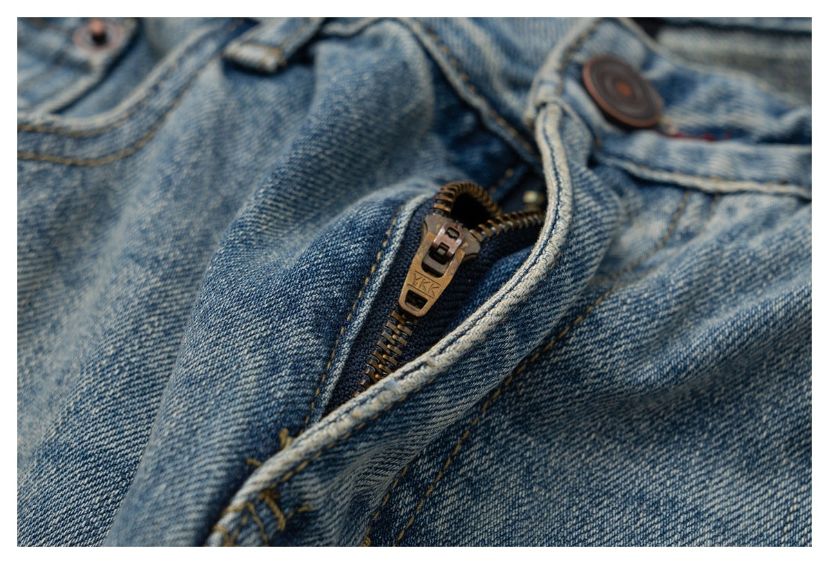 Close-up of faded blue jeans with the metal fly zipper partly open.