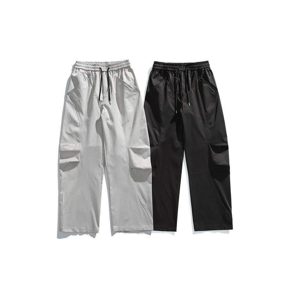 Front view of light gray and black loose-fit trousers with elastic waistbands, drawstrings, and cargo-style knee details.