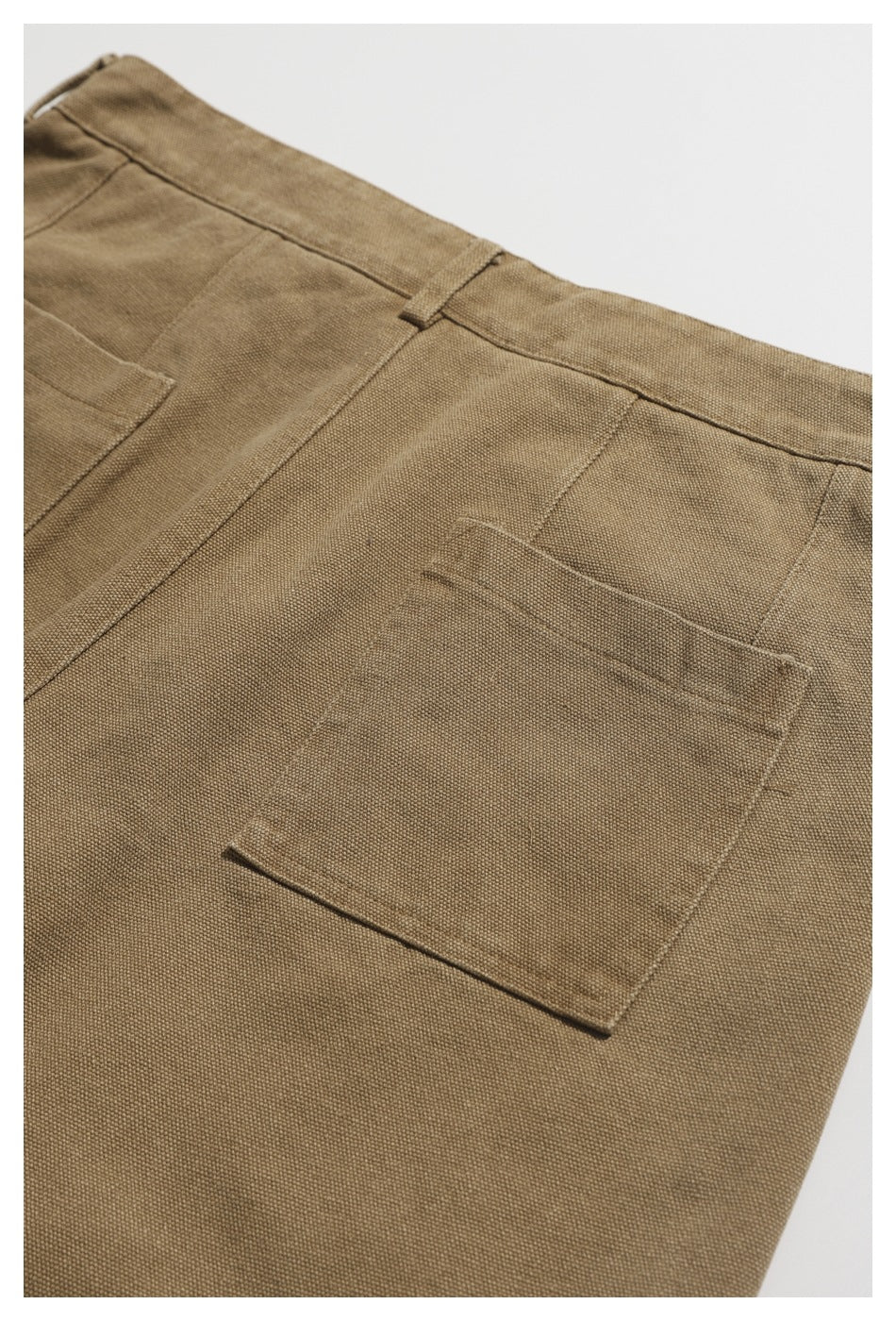 Close view of the back of tan trousers laid flat, showing a plain rectangular patch pocket and waistband.