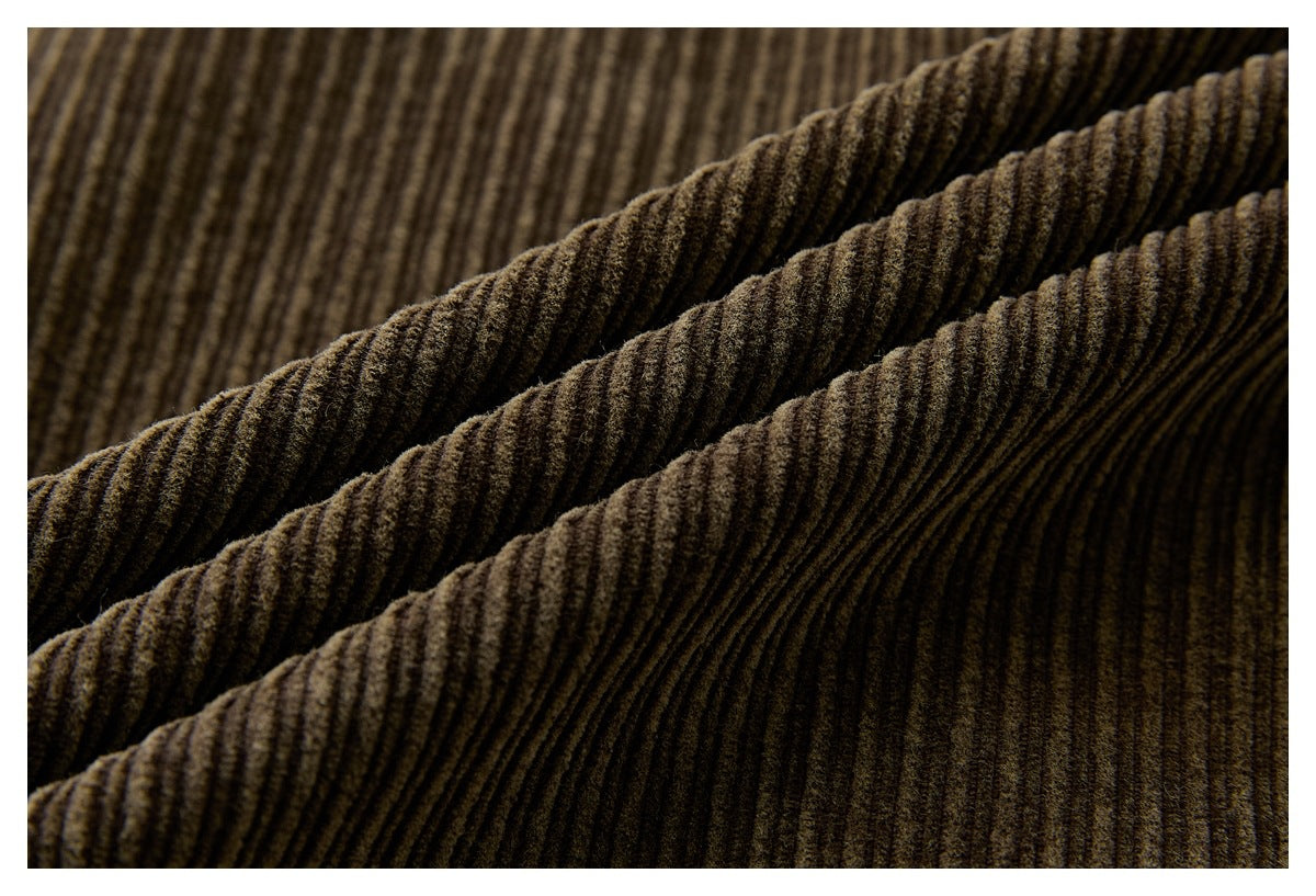 Close-up of dark brown ribbed corduroy fabric folded into soft diagonal ridges.
