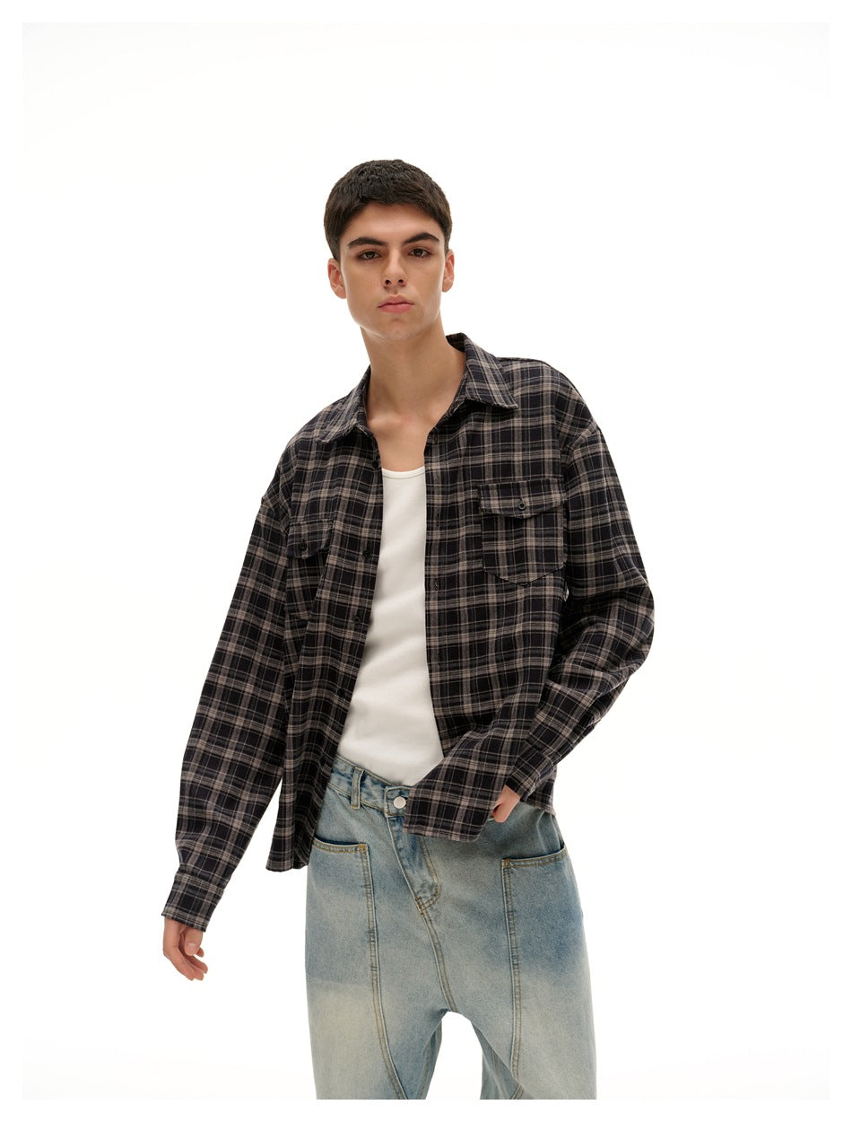 Model wearing an open dark charcoal plaid shirt over a white tank with light-wash wide-leg jeans.
