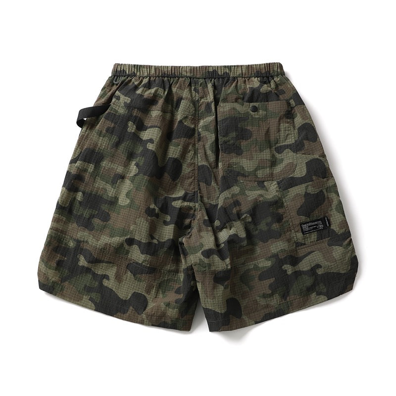 Front flat lay of camouflage shorts with an elastic waistband, black drawstring, and flap pocket.