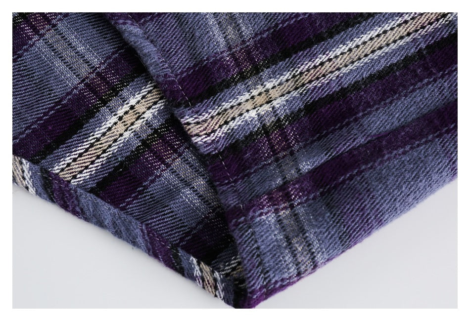 Close-up of a folded edge and seams on purple, blue, black, and cream plaid fabric.
