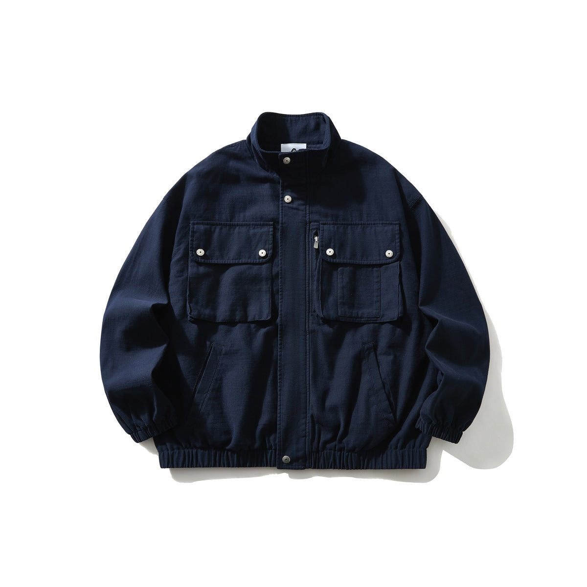 Navy stand-collar jacket with two large flap chest pockets, snap closures and elastic cuffs and hem, flat lay front view