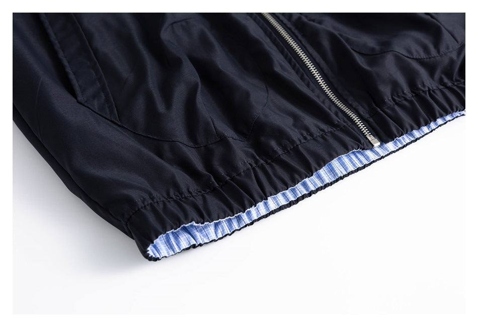 Close-up of a dark navy jacket's gathered hem, center zipper, and blue-and-white checked lining.