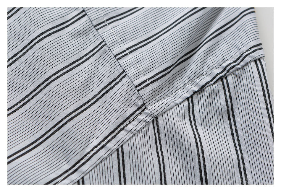 Close-up of striped light gray fabric with overlapping panels and a stitched edge.