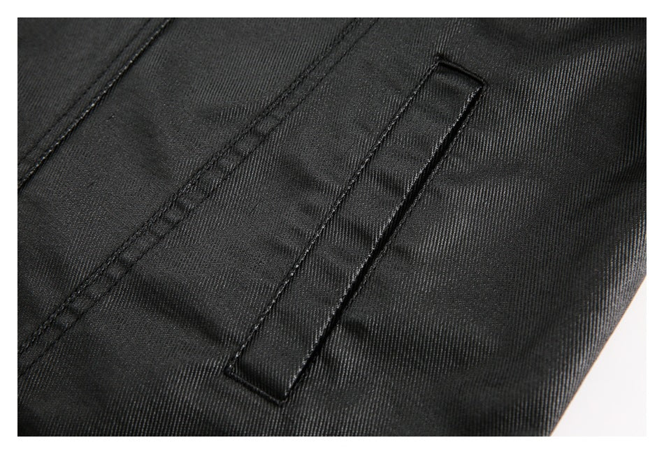 Close-up of a narrow welt pocket on the black jacket, with visible stitching.
