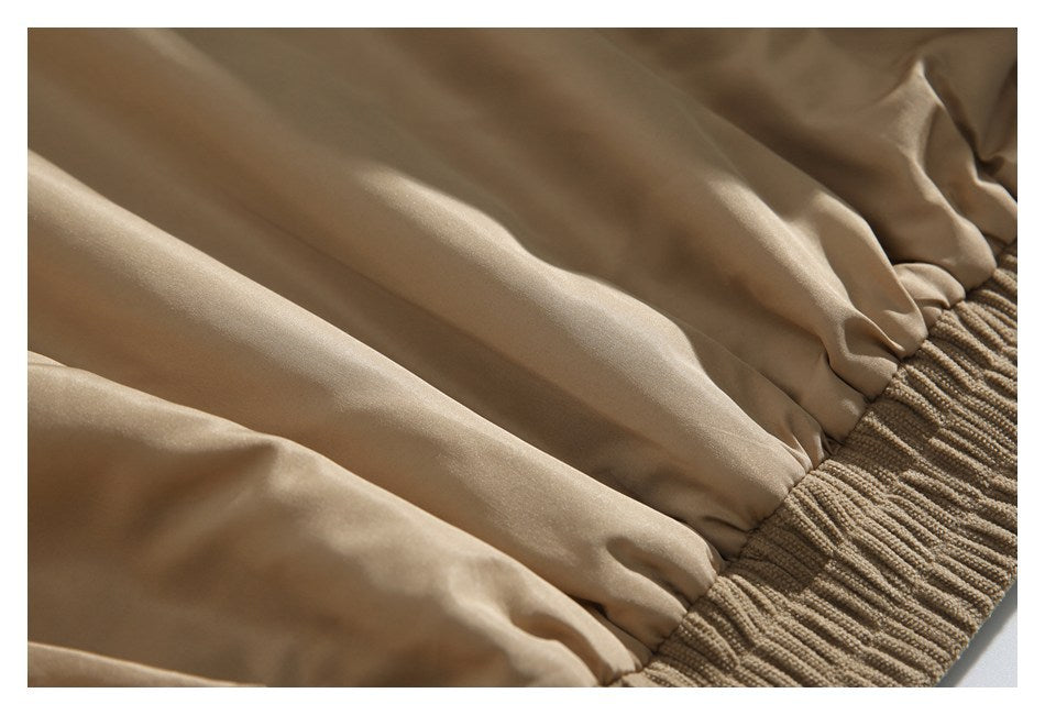 Close-up of smooth tan lining gathered beside a ribbed tan jacket hem.