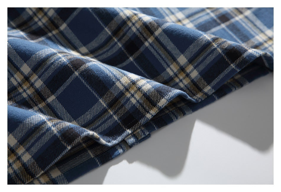 Close-up of blue and navy plaid fabric draped with its folded edge visible.
