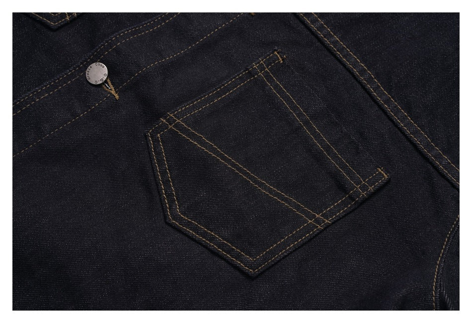 Close-up of a dark indigo denim jacket pocket with contrast topstitching and a small metal button.
