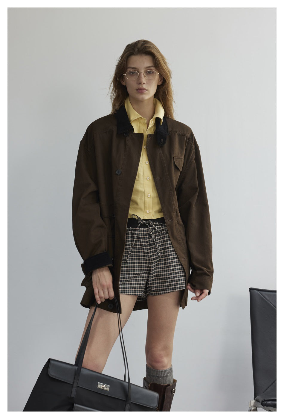 Model wearing an open dark brown utility jacket with a black collar and flap pockets.