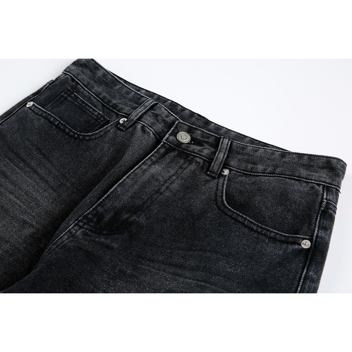 Close-up of black denim jeans showing the waistband, button, belt loops, and front pockets.