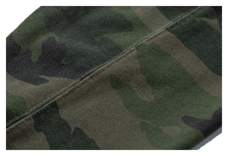 Close-up of a diagonal stitched seam across green camouflage fabric.