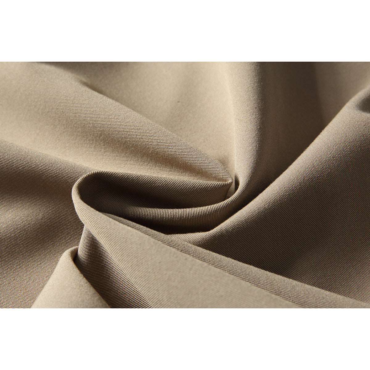 Macro view of beige trouser fabric folded to show its fine woven texture.