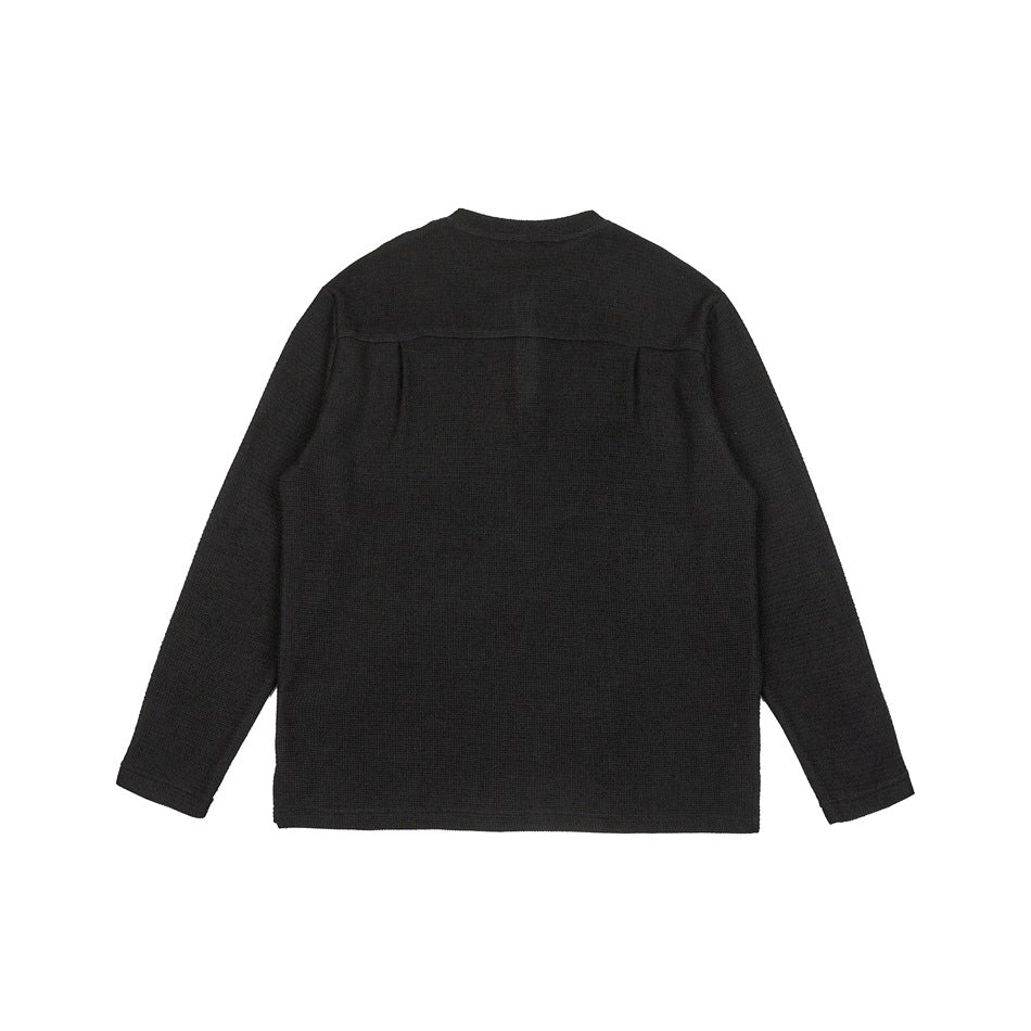 Back view of a black long-sleeve knit top laid flat against a white background.