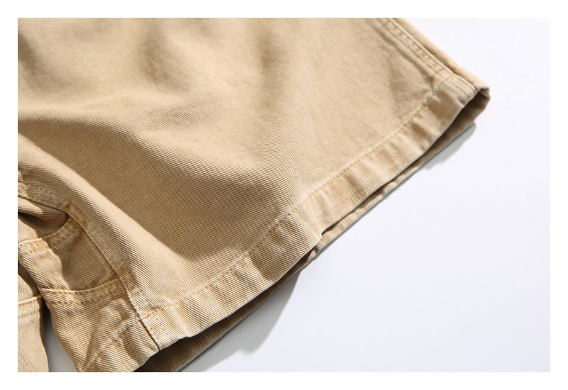 Close-up of the stitched hem and leg opening of tan trousers.