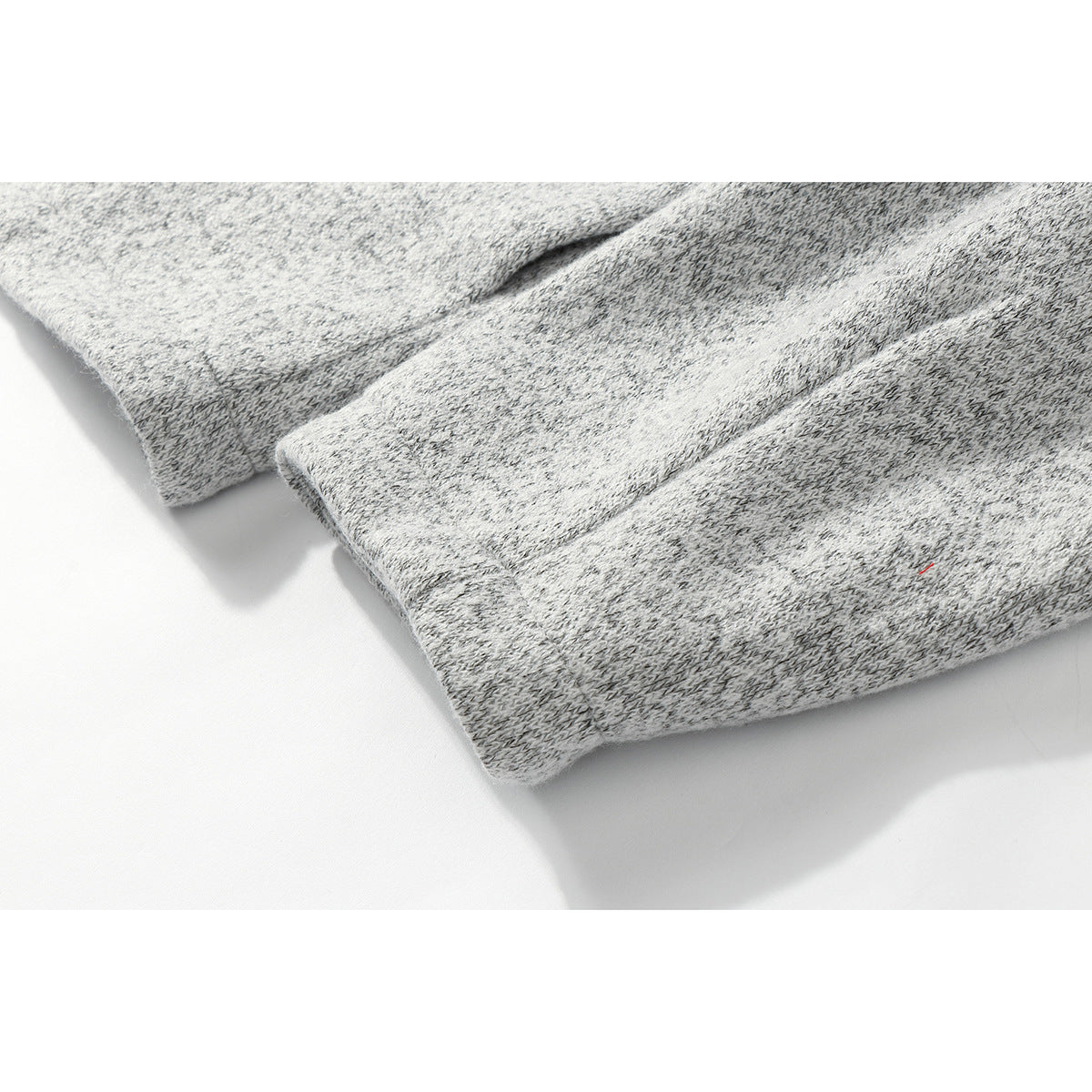 Close-up of the gray marled knit garment's ribbed sleeve cuff and stitching.